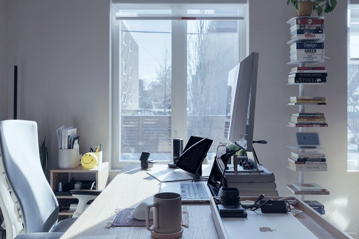 A bright home office with a large monitor and bookshelves.