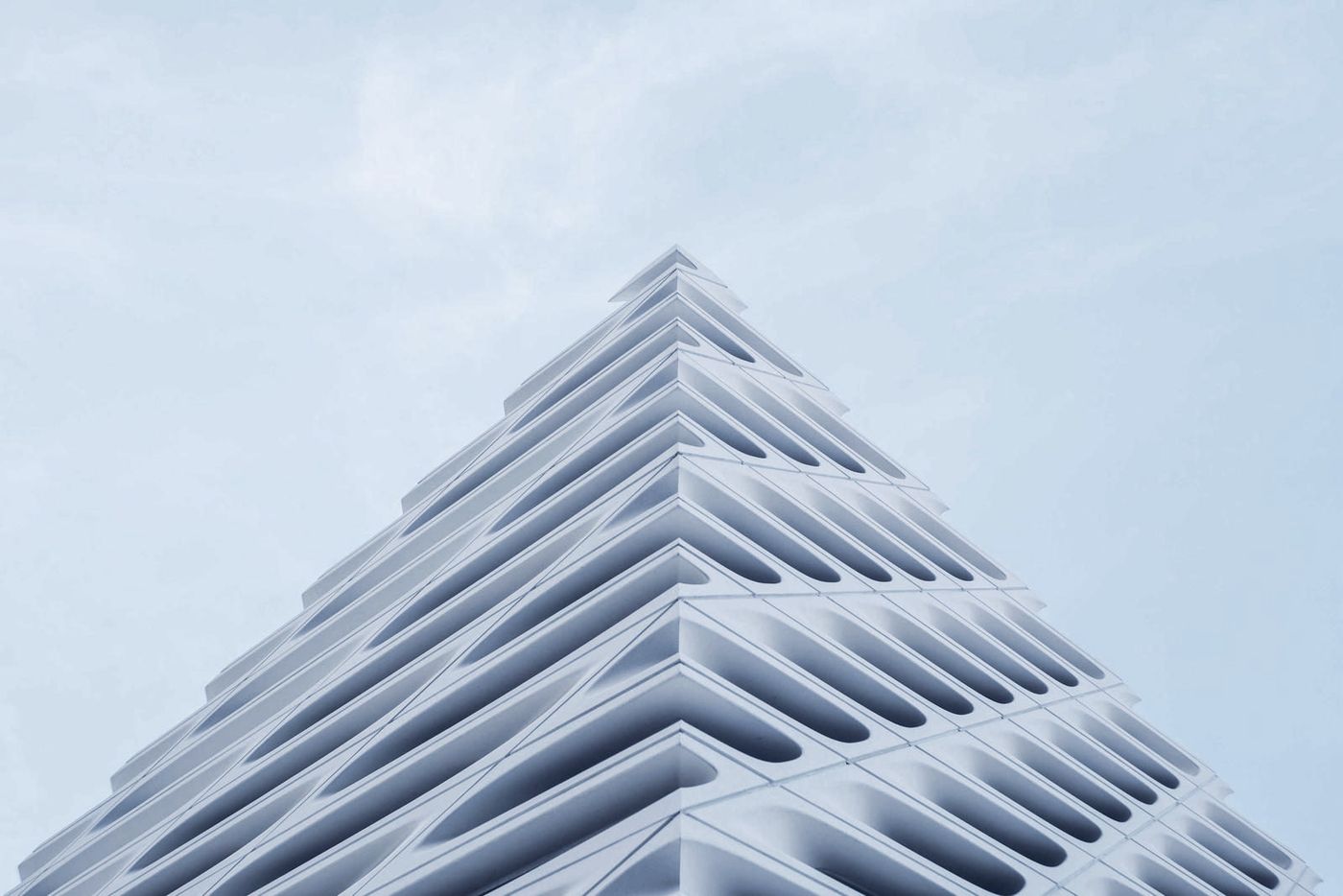 A modern white building rising into a pale sky.